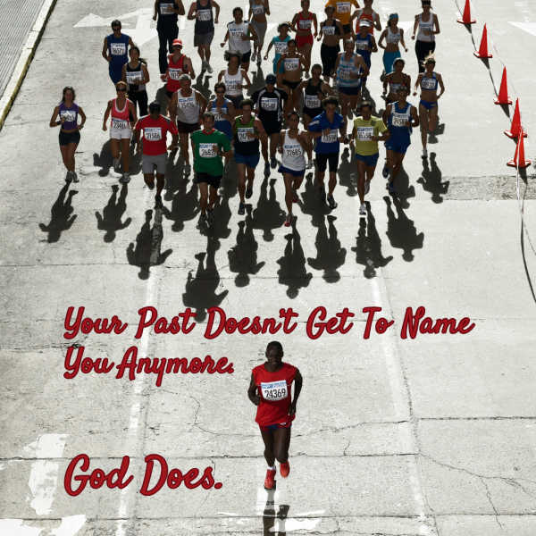 Photograph captures a road race, with one runner in a red shirt ahead of a large pack of competitors. Red lettering reads, “Your past does not define who you are; who defines you is God,” while orange cones, race bibs, long shadows, and cracked pavement frame scene.